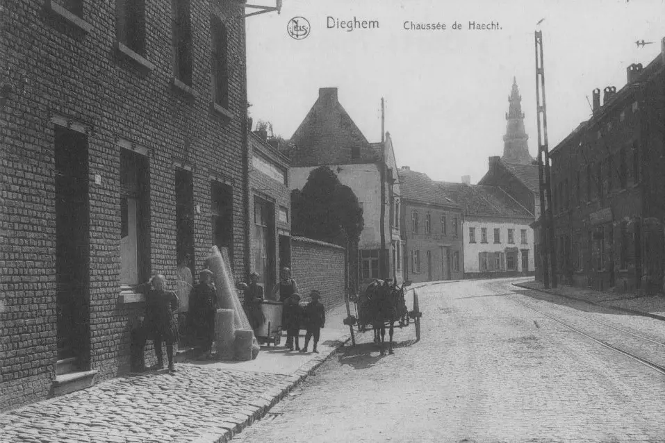 Oude prentkaart: straat met kar, de torenspits in de verte.