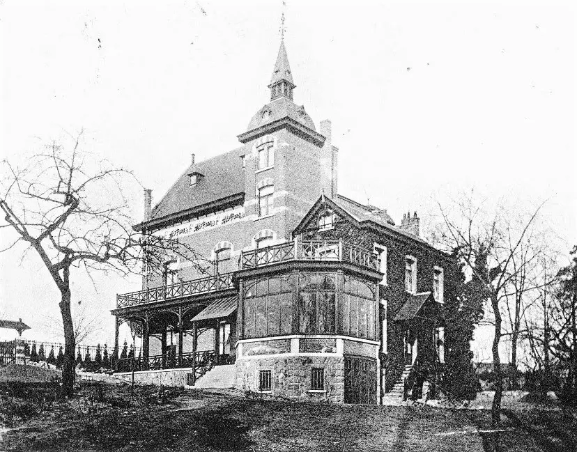 Oude foto van een villa tussen de bomen.