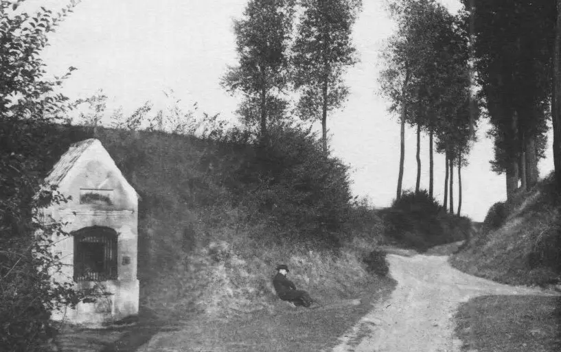 Oude foto: holle weg bij een witte kapel.